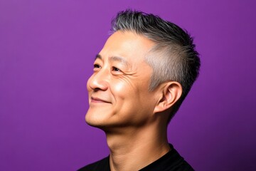 Obraz premium A studio shot capturing the essence of a modern man. Idea of style for aging men. Purple solid background. Fashionable men's wavy fringe haircut - midlife asian man with short hair.