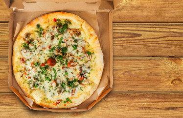 Photo of mushroom pizza in cardboard box on wooden table.