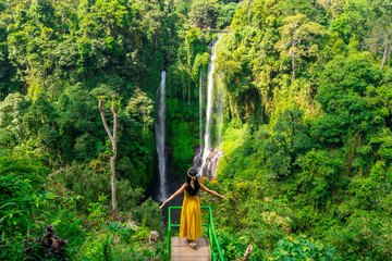 Young Asian woman traveler enjoying at Sekumpul waterfall the tourist destination in Bali, Indonesia