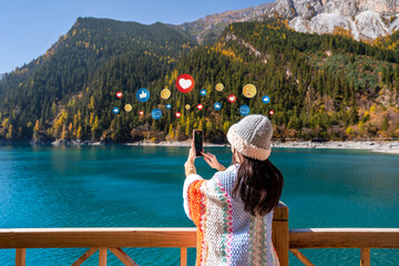 Young female tourist enjoying and taking a photo at beautiful autumn scenery landscape at jiuzhaigou national park in Sichuan, China