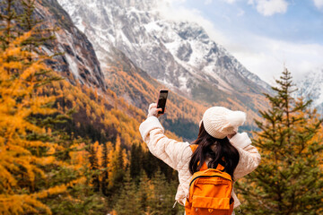Young female tourist relaxing and enjoying at beautiful autumn scenery landscape at Mount Siguniang national park in Sichuan, China