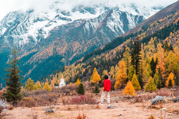 Young man traveler relaxing and enjoying at beautiful autumn scenery landscape at Mount Siguniang national park in Sichuan, China