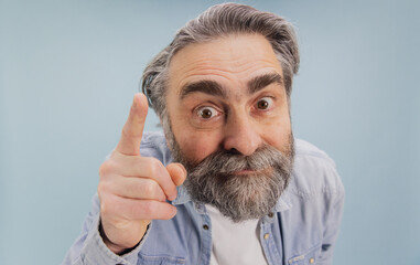 Expressive Senior Man Pointing Finger on Blue Background