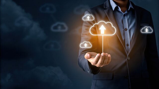 A businessperson holds a glowing cloud icon with an upload arrow, representing cloud computing and digital data storage. - Powered by Adobe