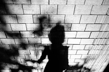 Shadow silhouette of women walking city street sidewalk in black and white high contrast