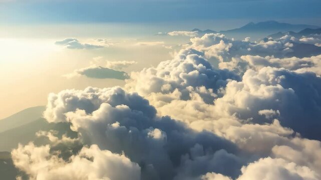 Aerial view of fluffy white cumulus clouds with mountains in the distance under a bright sky, conveying a sense of peace and tranquility.