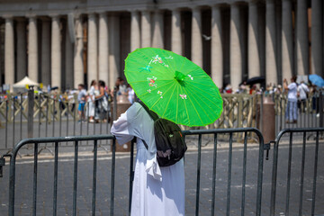 Religious man in a white monastic habit and a green umbrella.