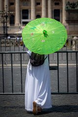 Religious man in a white monastic habit and a green umbrella.
