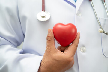 Asian woman doctor holding red heart for health in hospital.