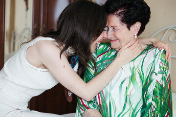 Granddaughter hugging her grandmother while smiling with joy

