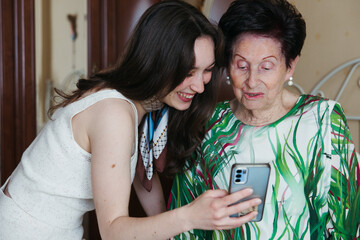 Granddaughter showing a phone message to her smiling grandmother