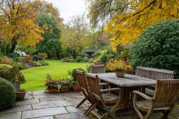 Obraz premium Outdoor patio with wooden table and chairs overlooking a lush green lawn and colorful autumn trees.