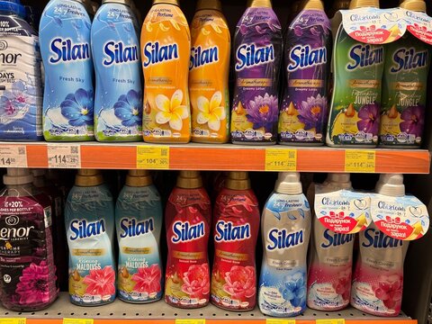 Various silan fabric softener bottles are neatly arranged on a supermarket shelf, showcasing different scents and promotional offers, creating a vibrant and colorful display for consumers