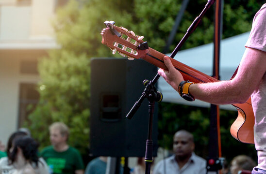 Close up of musician playing guitar playing on a summer music festival on an urban area