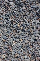 Pebbles on a beach background backdrop in various shapes, sizes and colours.