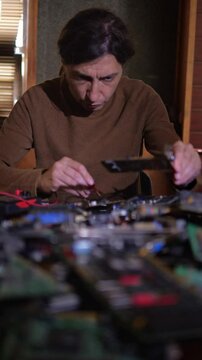 A focused and technical mood is captured as a person uses a multimeter to test components on a circuit board, with other electronics blurred in the foreground