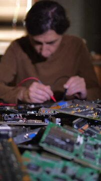 A deep and technical mood is captured by a close-up of computer circuit boards and components in the foreground, with a blurred technician actively working on them in the background