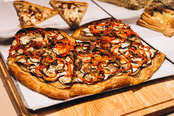 Fresh vegetarian pizza with colorful toppings displayed in bakery window.