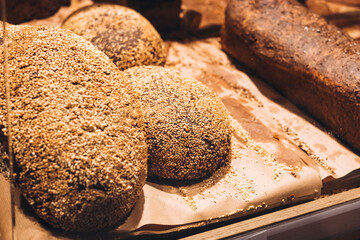 Freshly baked sesame bread displayed in bakery window, golden crust and seeds.