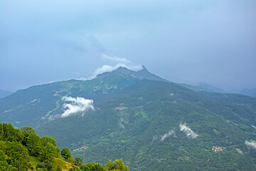 White fluffy cloud along a green mountain peak n Vanoise national park, France 