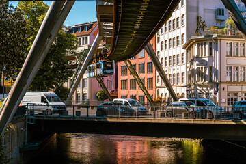 Eine Schwebebahn fährt zwischen alten Industriegebäuden in der Nähe der Haltestelle Kluse,...