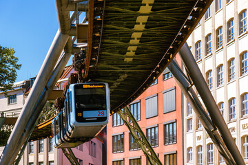 Eine Schwebebahn fährt zwischen alten Industriegebäuden in der Nähe der Haltestelle Kluse,...