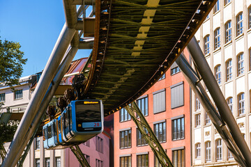 Eine Schwebebahn fährt zwischen alten Industriegebäuden in der Nähe der Haltestelle Kluse,...