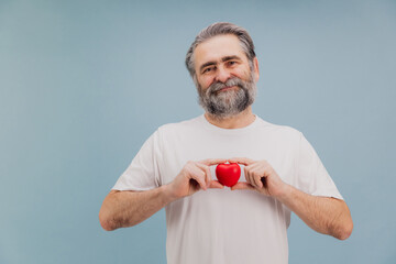 Senior man holding red heart promoting heart health and medical awareness