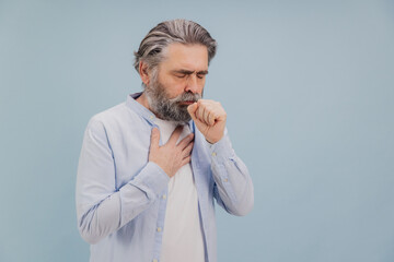 Senior man coughing and holding his chest suffering from illness