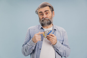Confused senior man pointing at blister packs with pills