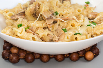Cooked curved pasta with mushrooms in white souse, front view