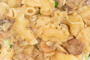 Cooked curved ruffled pasta with mushrooms in white souse, fragment