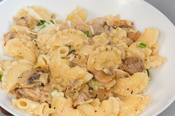 Cooked curved ruffled pasta with mushrooms in white souse, fragment