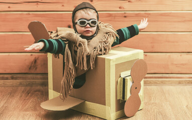 Flying child flying with cardboard wings. Kid dreams of pilot. Baby fly with paper plane. Boy in aviator helmet indoors. Child flying with toy airplane. Dreaming kid Flying in cardboard box.