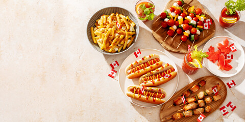 Border of Canada Day party food with poutine, hot dogs, decorated with Canadian flag, copy space