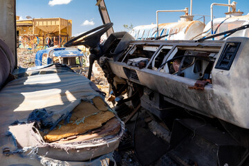 Decayed truck interior in junkyard – destroyed driver’s cabin with torn seat and missing dashboard