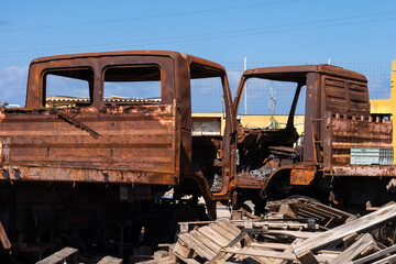 Two completely rusted trucks on an abandoned junkyard