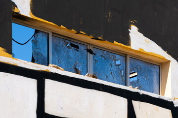 Broken windows in an abandoned building – close-up of urban destruction with facade marks and light effects