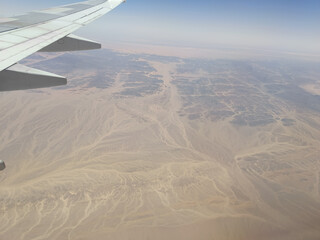 Aerial view from airplane over desert landscape with wing in frame