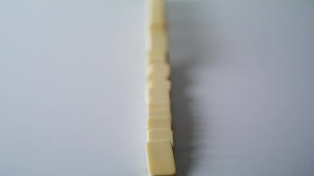 Hand destroying domino row on surface closeup. Unrecognizable man pushing blocks