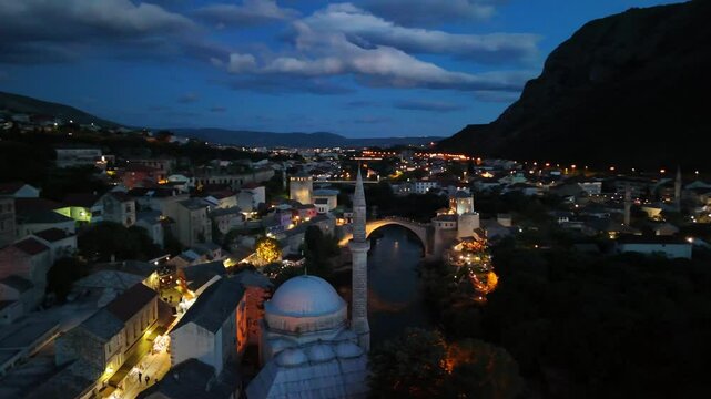 Aerial drone view of the Old Town and the Old Bridge at night in Mostar, Bosnia and Herzegovina. Panoramic view of the historic town and the Neretva River at night.