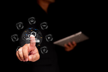 A person interacts with a digital interface showing a globe and "UPDATING" status, surrounded by technology icons, while holding a tablet.