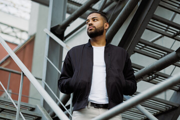 Young african american man in bomber jacket standing on fire escape