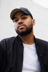Portrait of stylish african american man in baseball cap looking at camera outdoors