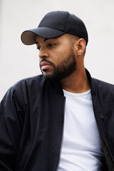 Portrait of african american man in baseball cap and bomber jacket outdoors