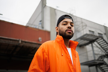 Portrait of serious african american man in baseball cap and vivid windbreaker on street