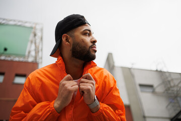 African american man in baseball cap wearing windbreaker jacket on street