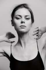 Fototapeta premium Elegant young woman posing confidently with a minimalist style in a black sleeveless top. Studio setting creates a striking monochrome effect highlighting her features.