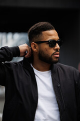 Portrait of african american man in sunglasses wearing bomber jacket outdoors 