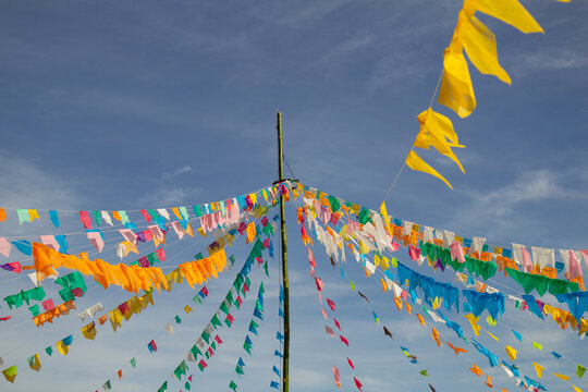 Um conjunto de bandeirolas coloridas penduradas com c&eacute;u ao fundo. Detalhe de um varal de bandeirolas em primeiro plano. Decora&ccedil;&atilde;o para quadrilha - festa t&iacute;pica brasileira.